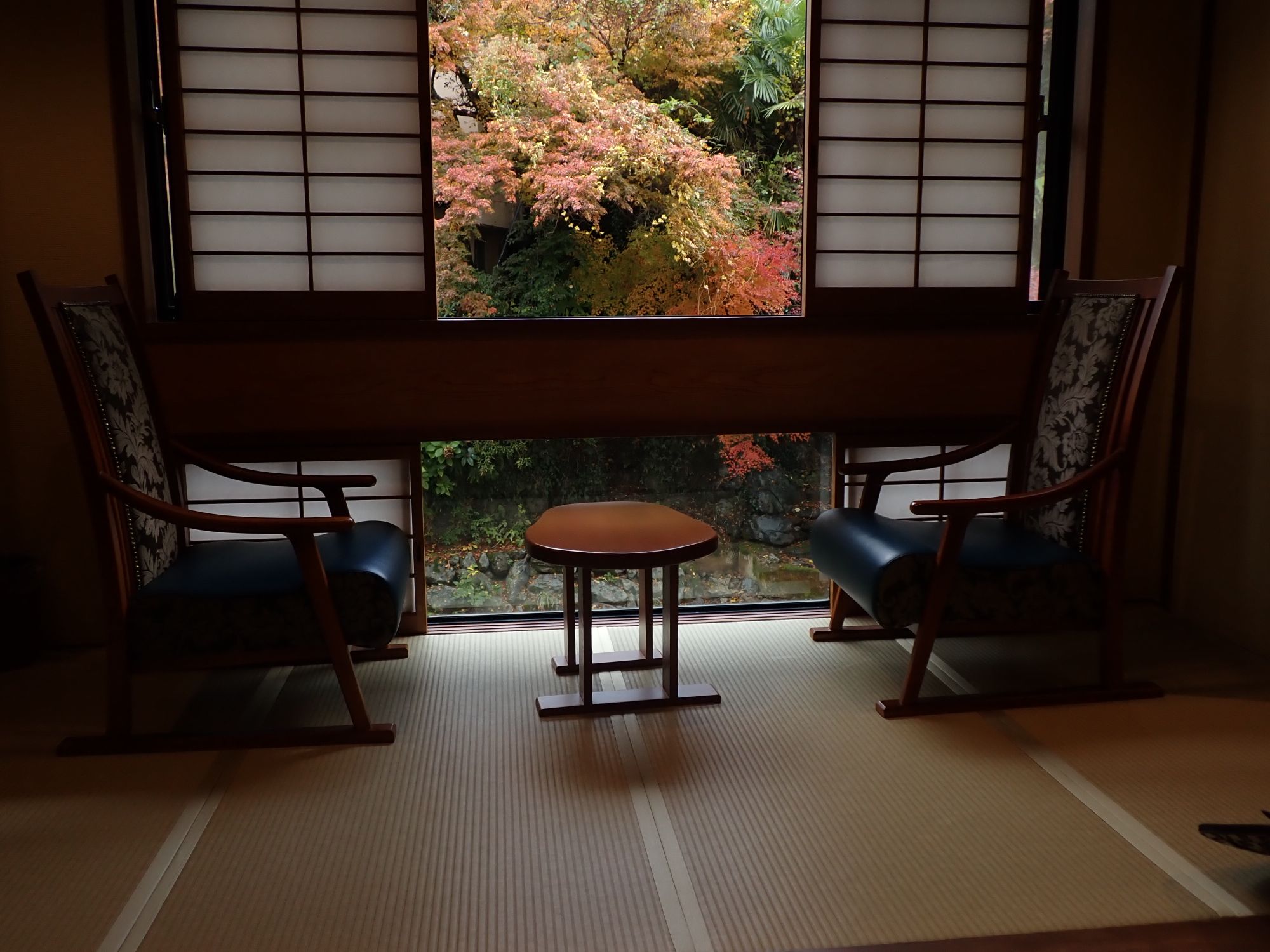 Two chairs in a tatami room facing an autumn garden through shoji windows