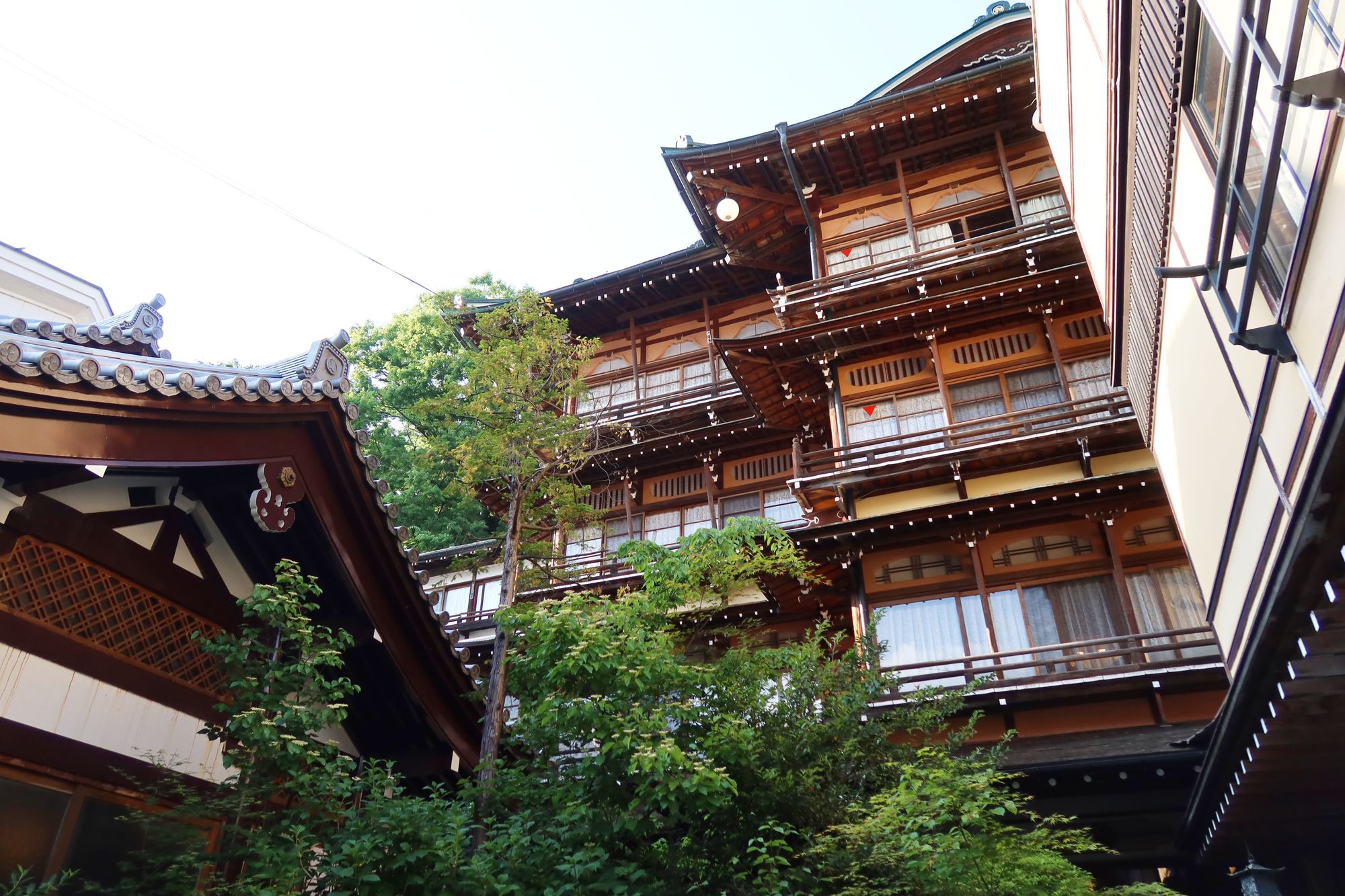 Wooden exterior of a traditional ryokan surrounded by greenery in Yamanouchi